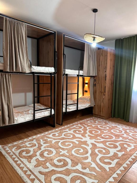 a room with two bunk beds and a rug at Hostel Saruu in Bishkek