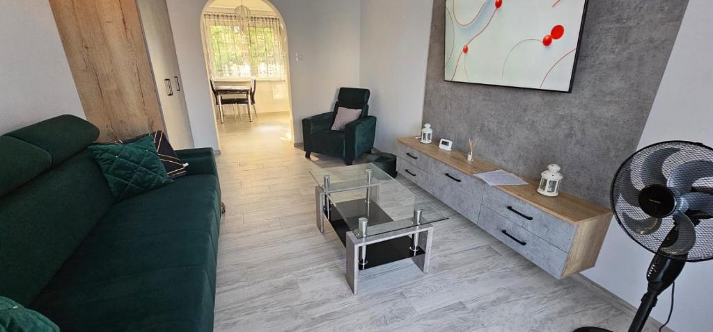 uma sala de estar com um sofá verde e uma mesa em Apartament Gabi em Giżycko