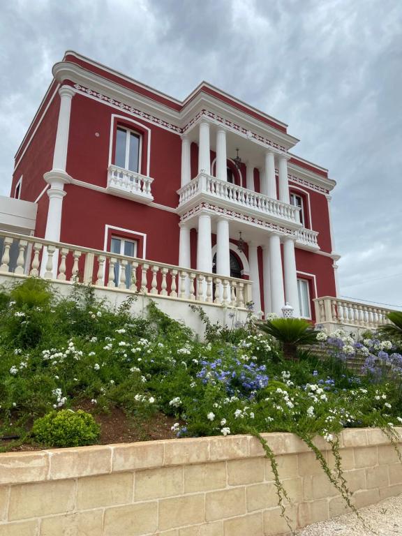 una casa roja con columnas blancas y flores en Six Star Boutique Hotel, en Monopoli