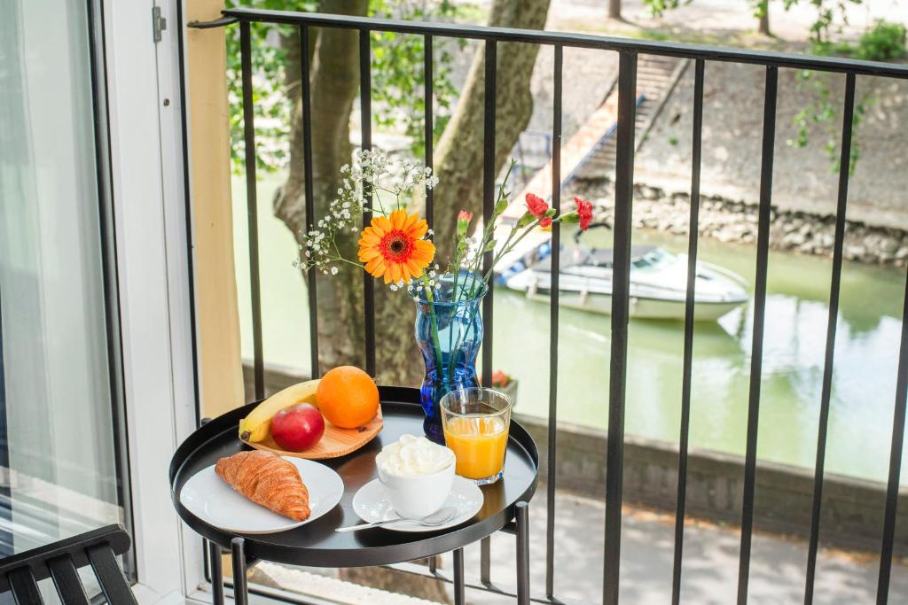 a table with breakfast foods and a vase of flowers on a balcony at Riverside Apartment No1 in Esztergom