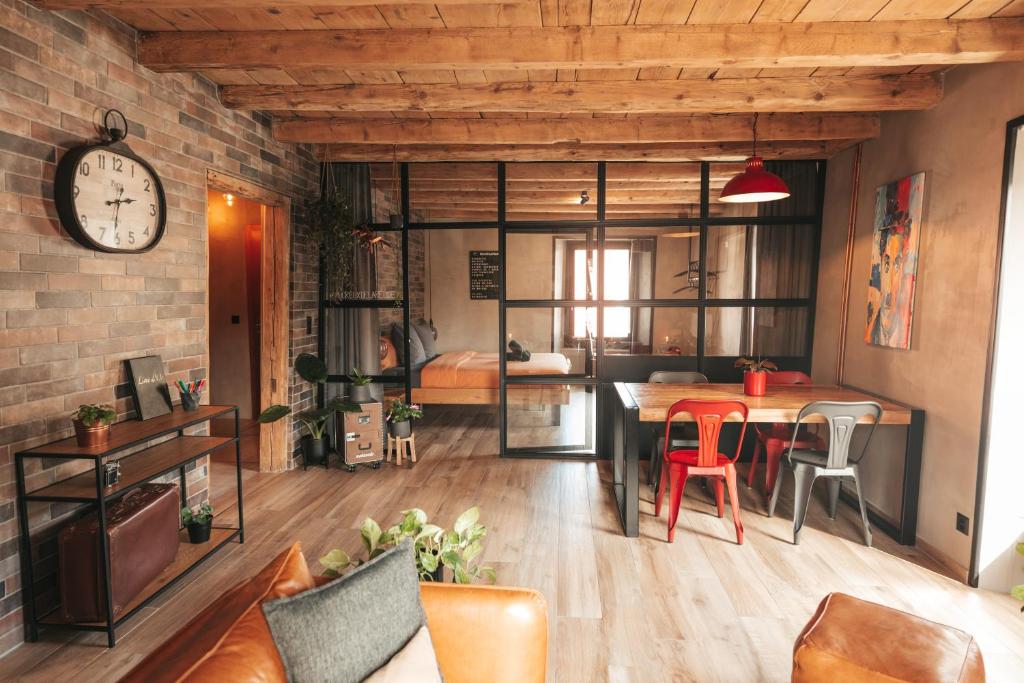 uma sala de estar com mesa e cadeiras e um relógio em Appartement thématique: Voyage Industriel em Travers