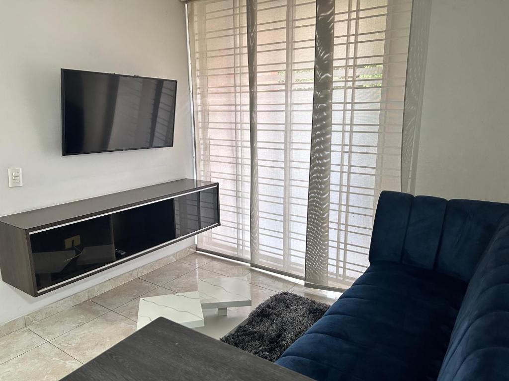 sala de estar con sofá azul y TV de pantalla plana en Cómodo apartamento 3 habitaciones, en Cúcuta