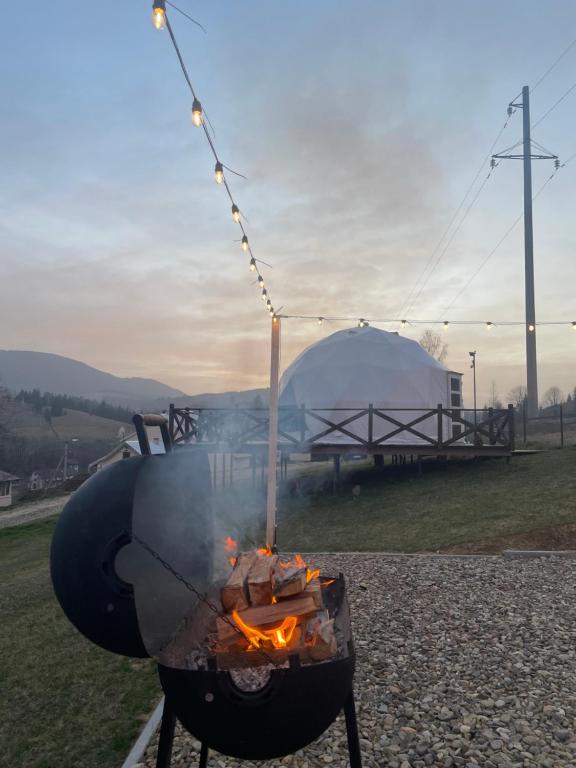 un barbecue con fiamme e una tenda sullo sfondo di Глемпінг Хатинка на полонині a Krivopolʼye