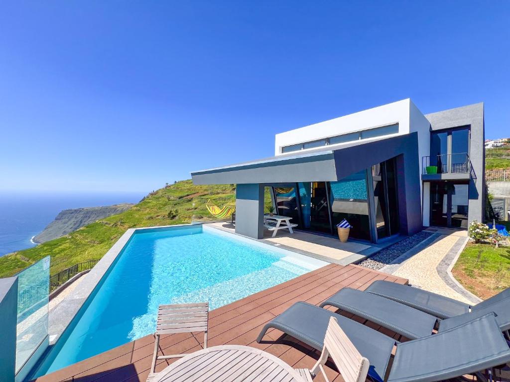 een huis met een zwembad aan de oceaan bij Villa Leonor Cliffside Retreat in Calheta