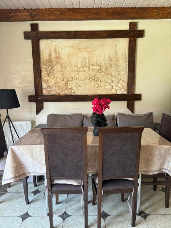 una mesa de comedor con sillas y una pintura en la pared en River House, en Yaremche