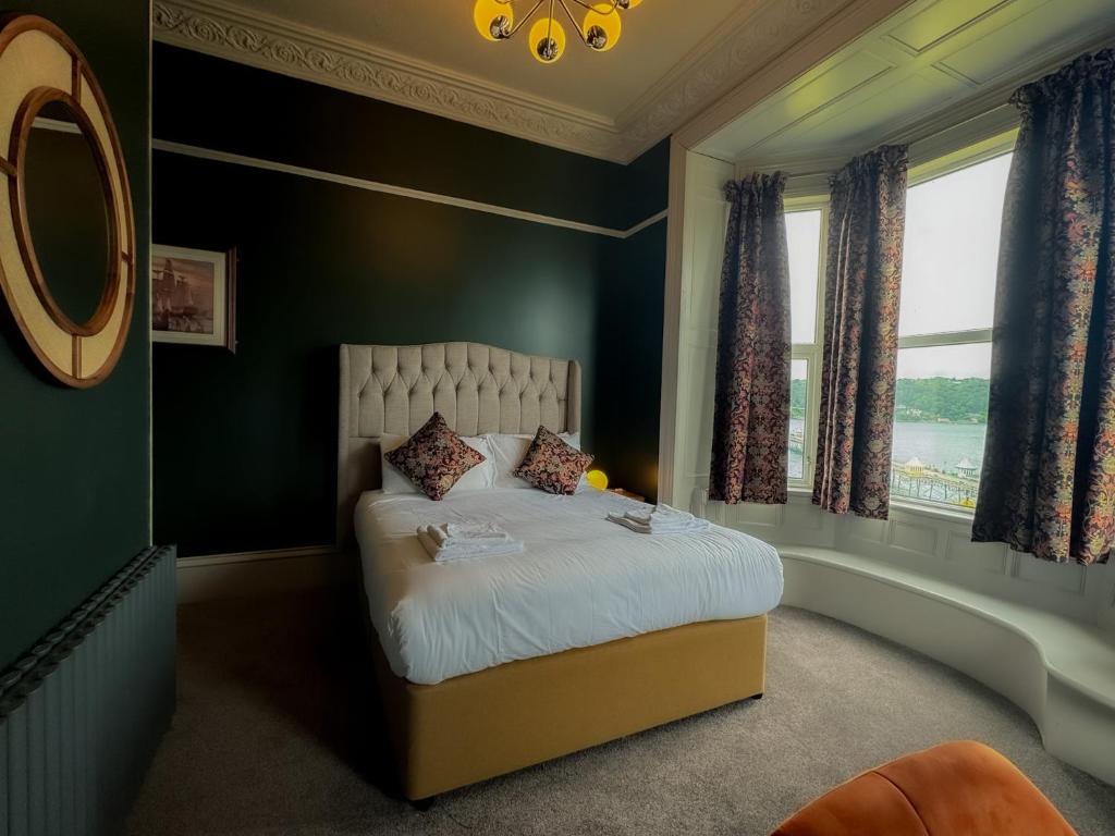 a bedroom with a bed with green walls and a window at Nomi Rooms & Restaurant in Bangor