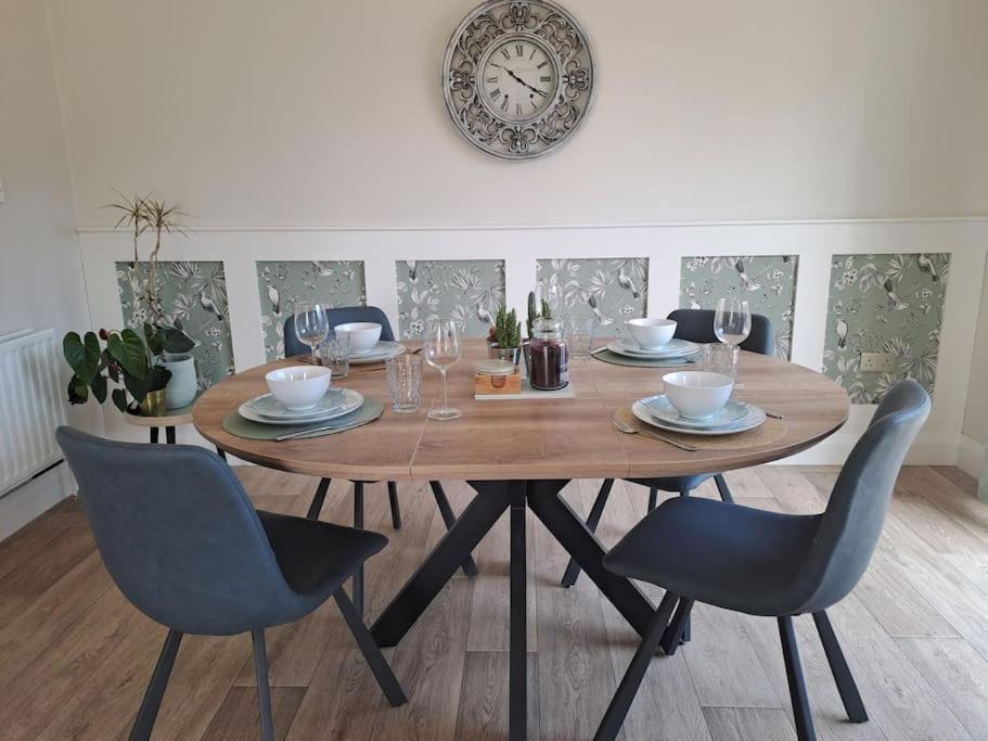 een houten tafel met stoelen en een klok aan de muur bij Fuchsia House in Killala