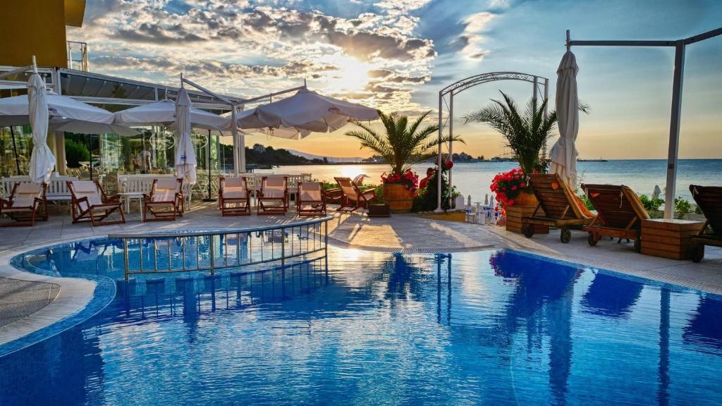 una piscina con sedie, tavoli e l'oceano di Aphrodite Beach Hotel a Nesebar