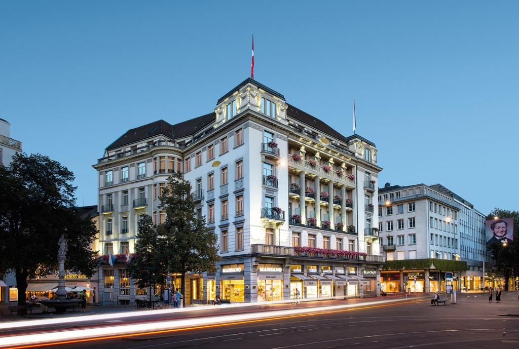 Mandarin Oriental Savoy, Zurich في زيورخ: مبنى ابيض كبير على شارع المدينة بالليل