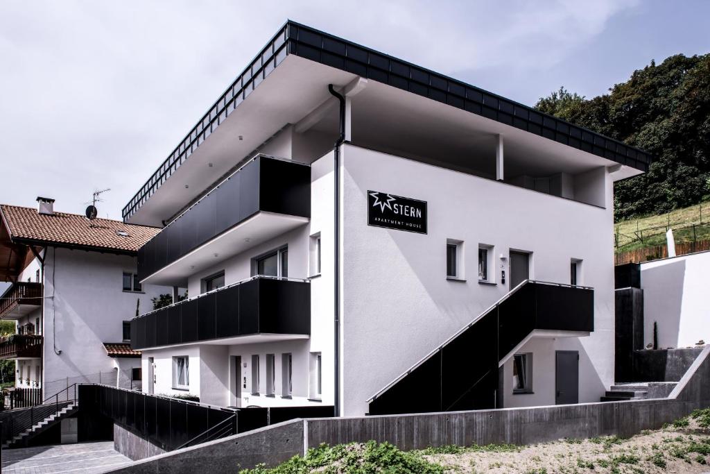 a white building with a black sign on it at Apartmenthouse STERN in Vipiteno