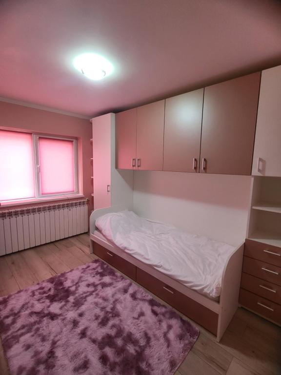 a bedroom with a bed and cabinets and a rug at Tudor Apartament in Ocna-Mureşului