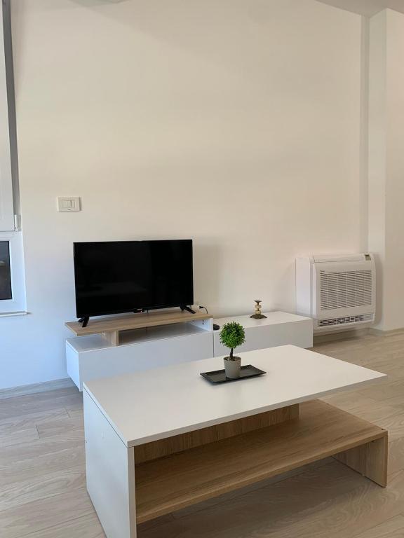 sala de estar blanca con TV y mesa en E&M Apartman, en Struga