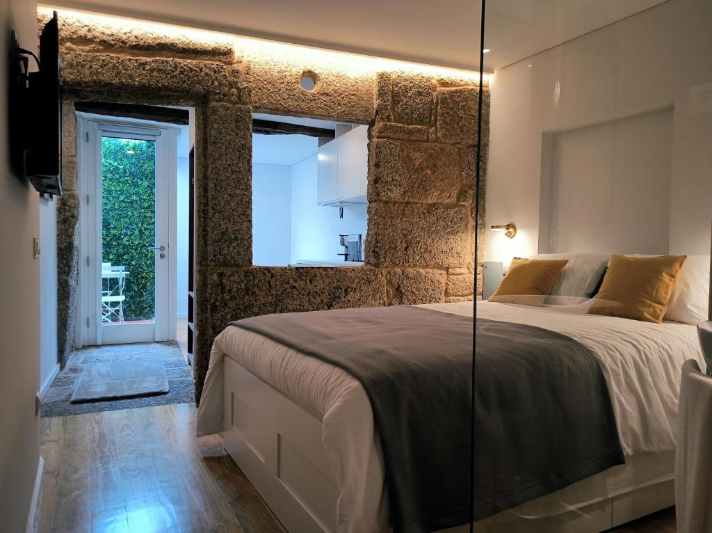 a bedroom with a large bed with a glass wall at DOMI Suites & Studios in Guimarães