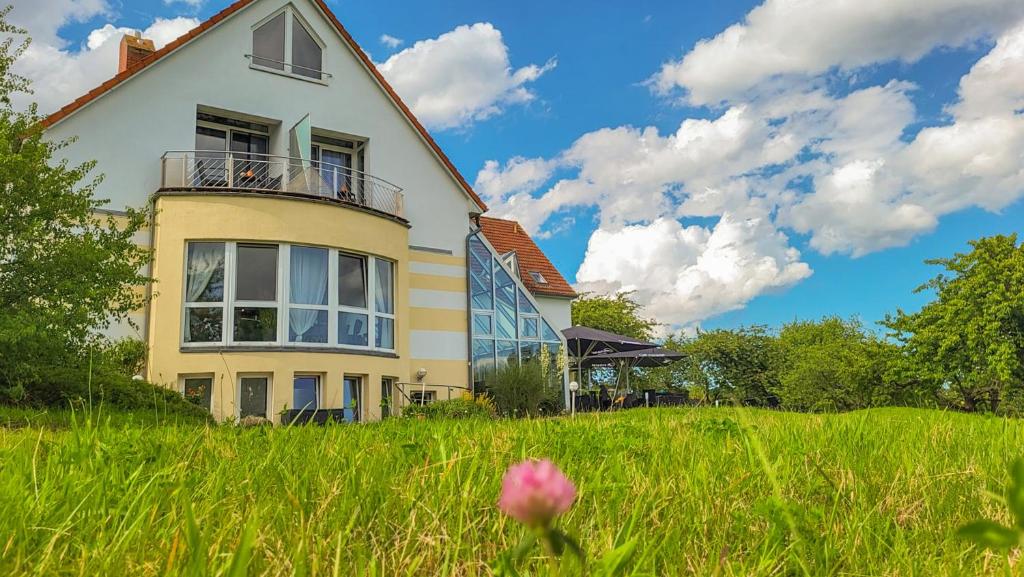 ein Haus auf einem grasbewachsenen Hügel mit einer rosa Blume im Vordergrund in der Unterkunft Inselhotel kleiner Bodden in Buschvitz