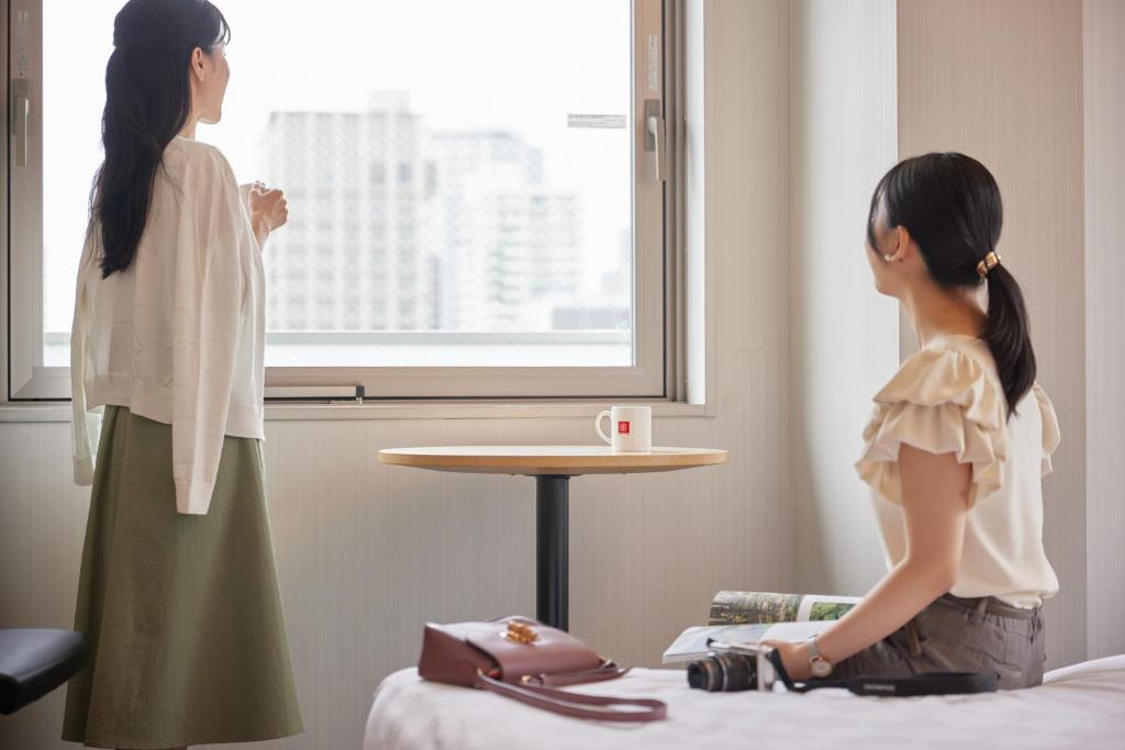 zwei Frauen aus dem Fenster in einem Hotelzimmer in der Unterkunft Kobe Motomachi Tokyu REI Hotel in Kōbe