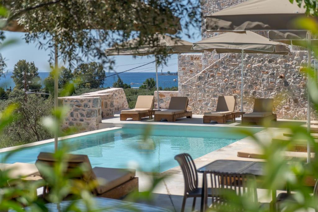 een zwembad met stoelen, een tafel en een parasol bij Istorima Guesthouse in Gythio