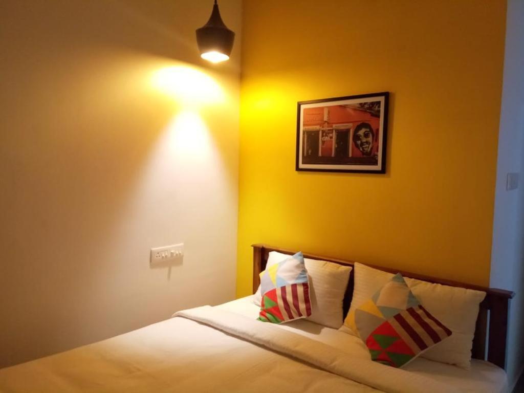 - une chambre dotée d'un lit avec un mur jaune dans l'établissement FULL moon, à Cochin