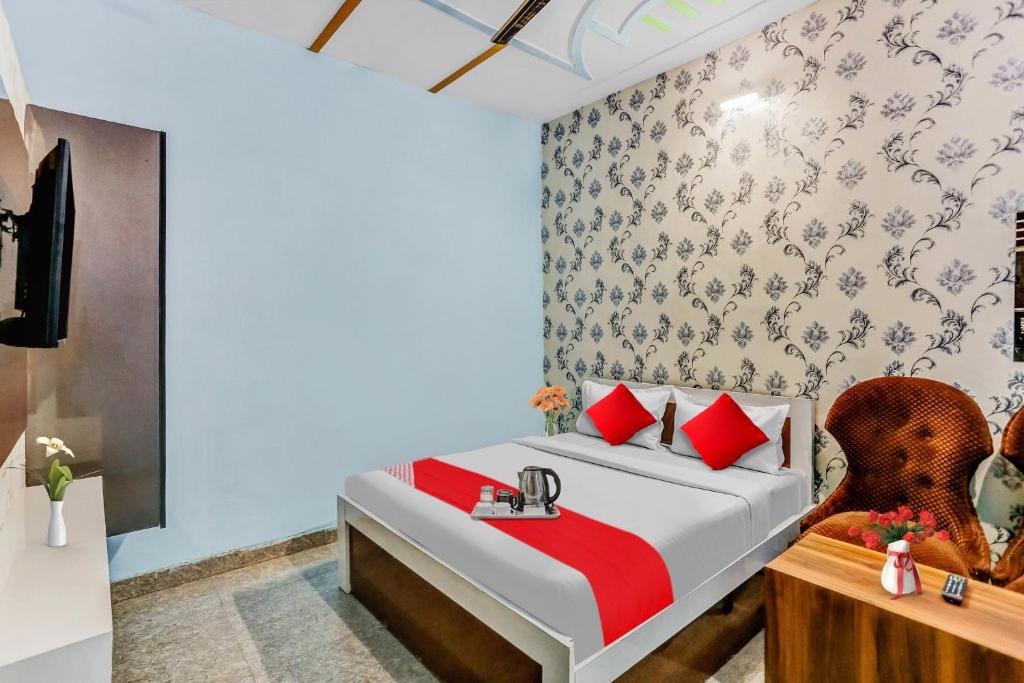 a bedroom with a bed with red pillows and a chair at Hotel O K D Guest House in Manesar