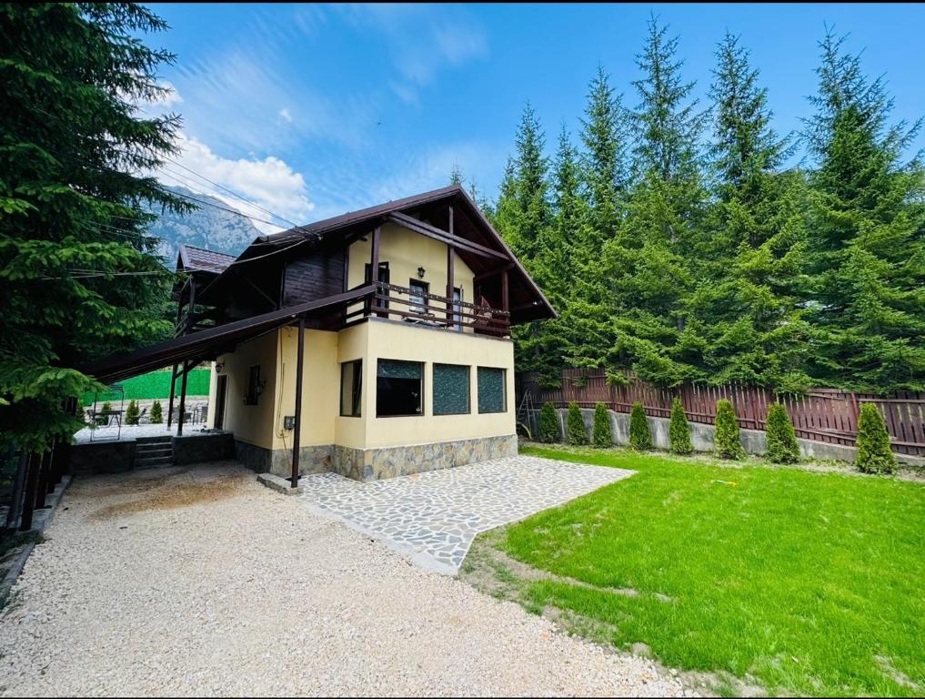 une maison avec un balcon au-dessus d'une cour dans l'établissement Ollie's Mountain Chalet, à Buşteni