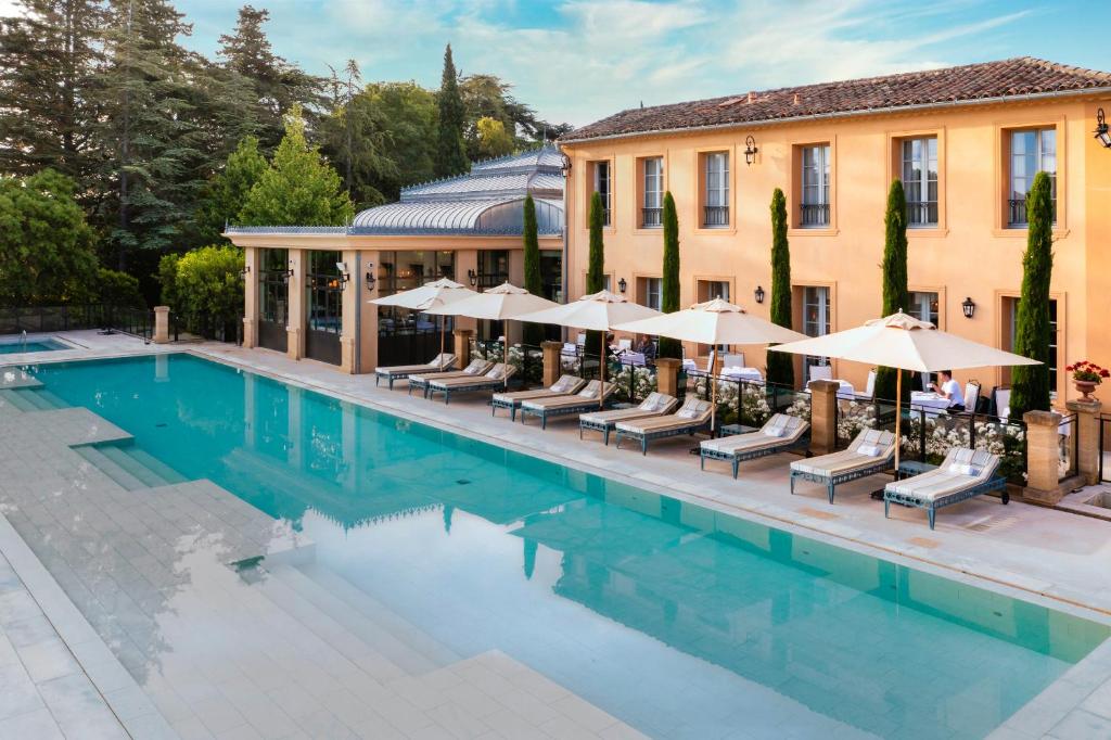 uma piscina com cadeiras e guarda-sóis ao lado de um edifício em Villa Saint-Ange em Aix-en-Provence