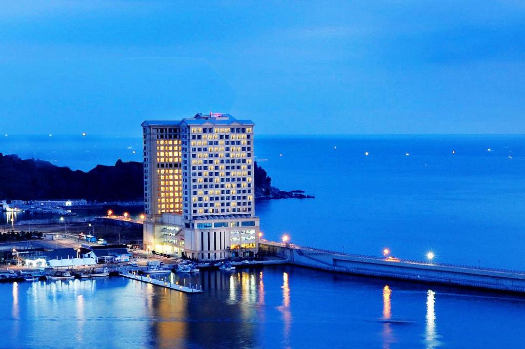 un grand bâtiment dans l'eau la nuit dans l'établissement Ramada by Wyndham Gangwon Sokcho, à Sokcho