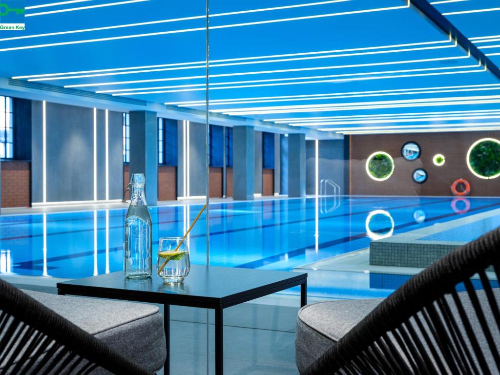 - une bouteille de verre sur une table en face de la piscine dans l'établissement Mercure Krakow Fabryczna City, à Cracovie