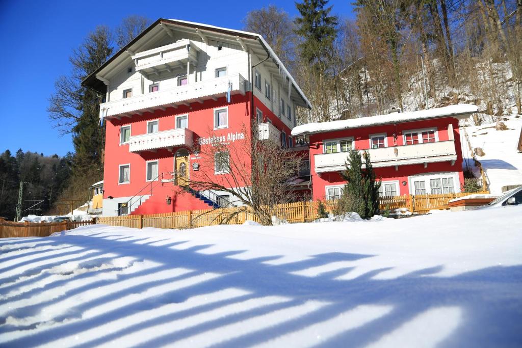 un grande edificio rosso con neve per terra di Gästehaus Alpina a Berchtesgaden