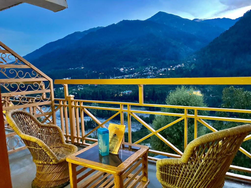 The Vashisht, Manali - A Four Star Luxury Hotel في مانالي: طاولة وكرسيين على شرفة مطلة