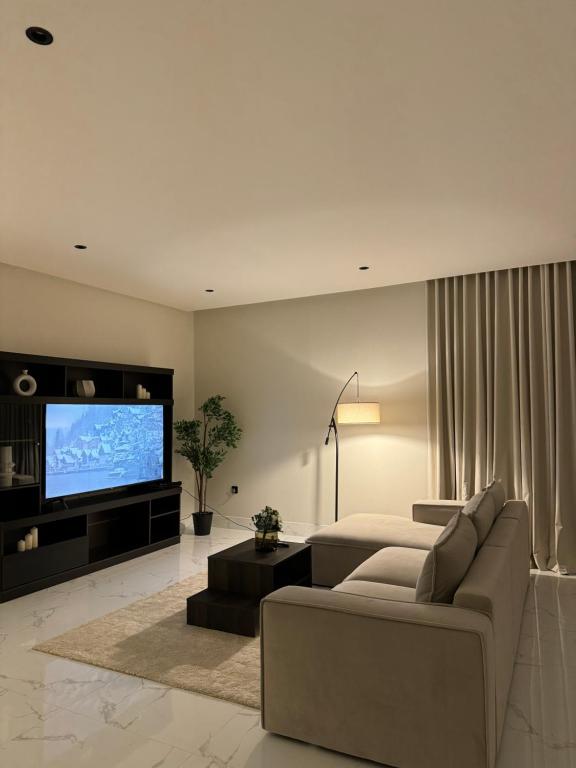 sala de estar con sofá y TV de pantalla plana en Sunrise Luxury Two Bedroom Apartment, en Al Khobar