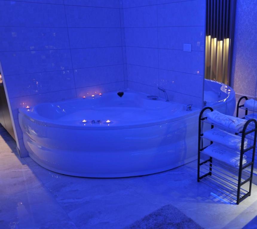 a large white tub in a bathroom with lights at Jacuzzi Apartman De Lux - Cacak in Čačak