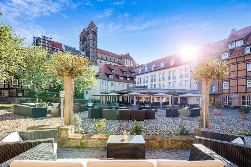 um pátio com mesas, árvores e edifícios em Best Western Hotel Schlossmühle Quedlinburg em Quedlinburg