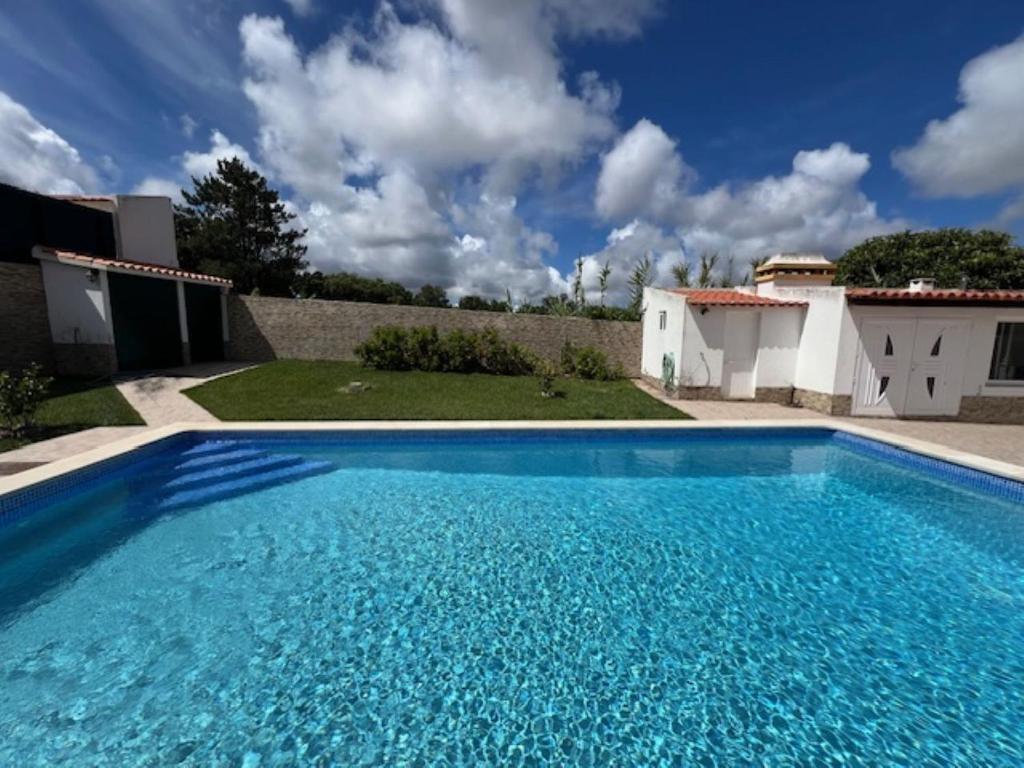 uma grande piscina azul em frente a uma casa em Quinta do Marmeleiro em Santiago do Cacém