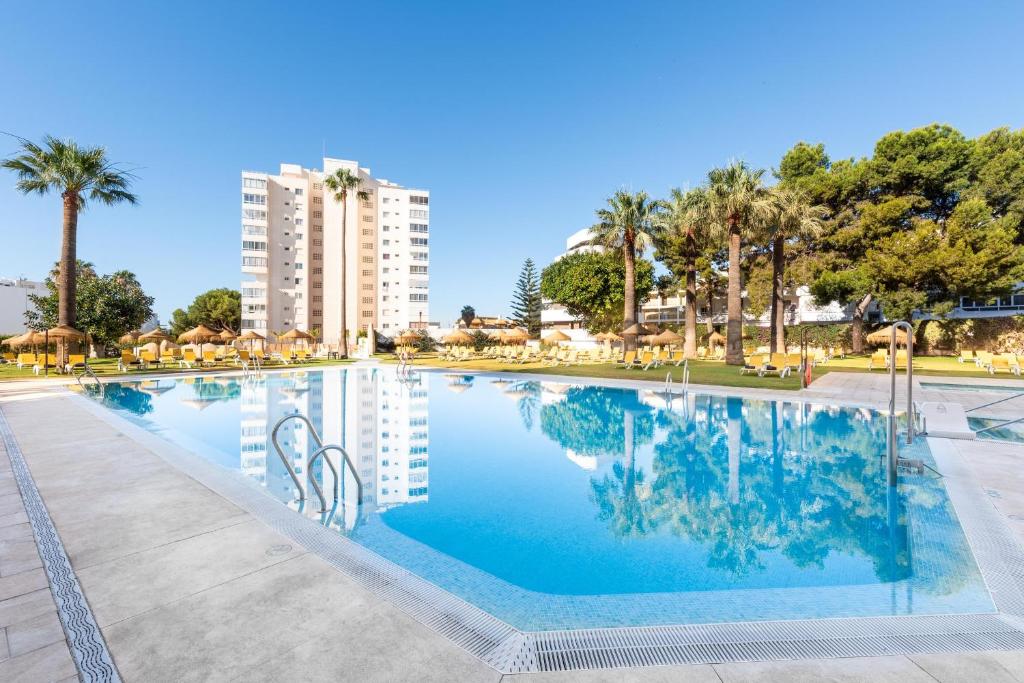 una piscina con palme e un edificio di THB San Fermín a Benalmádena