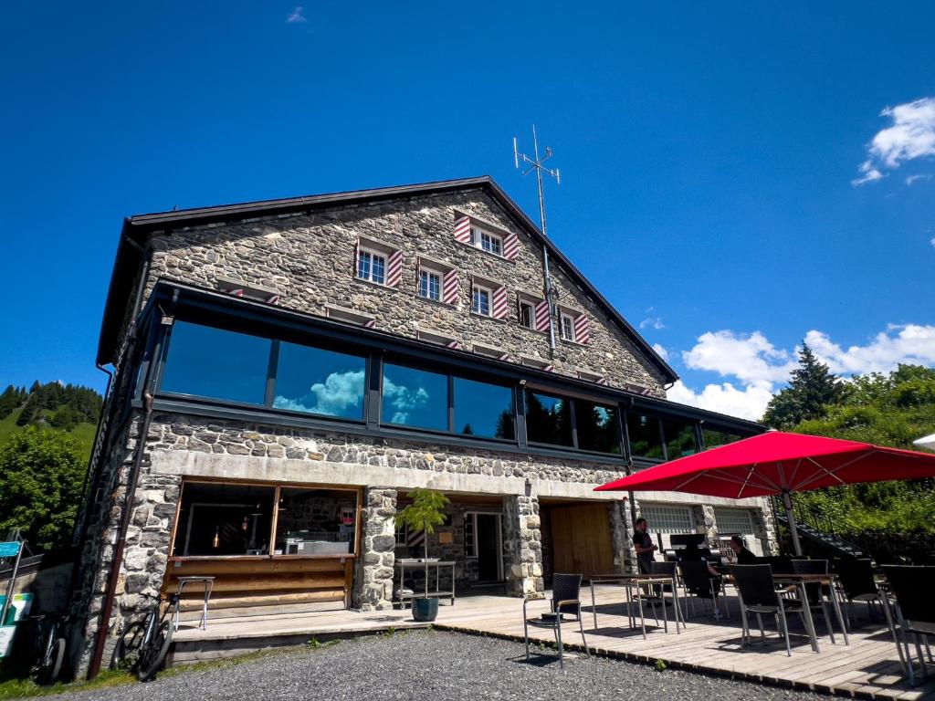 ein Gebäude mit einem roten Regenschirm davor in der Unterkunft Maison de Montagne de Bretaye accès par le train arrêt Bouquetin in Villars-sur-Ollon