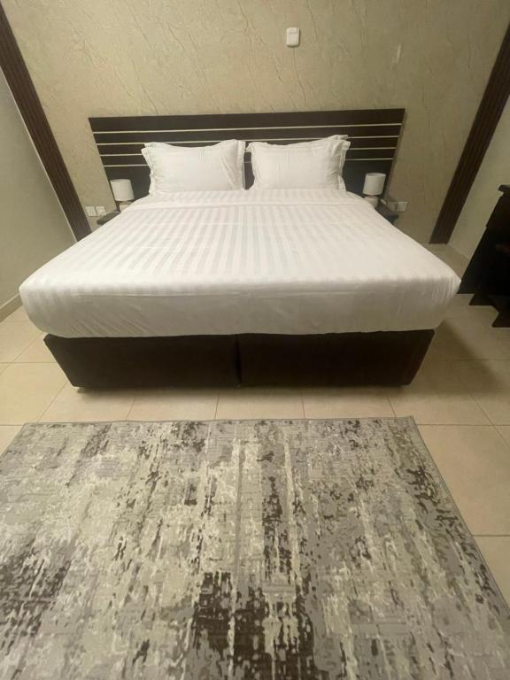 - un lit avec des draps blancs et un tapis dans une chambre dans l'établissement فالي ريزيدينس - Valley Residence, à Al Baha