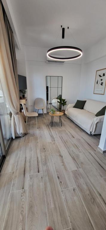 uma sala de estar com um sofá branco e pisos em madeira em Casa di Bello em Arkoudi