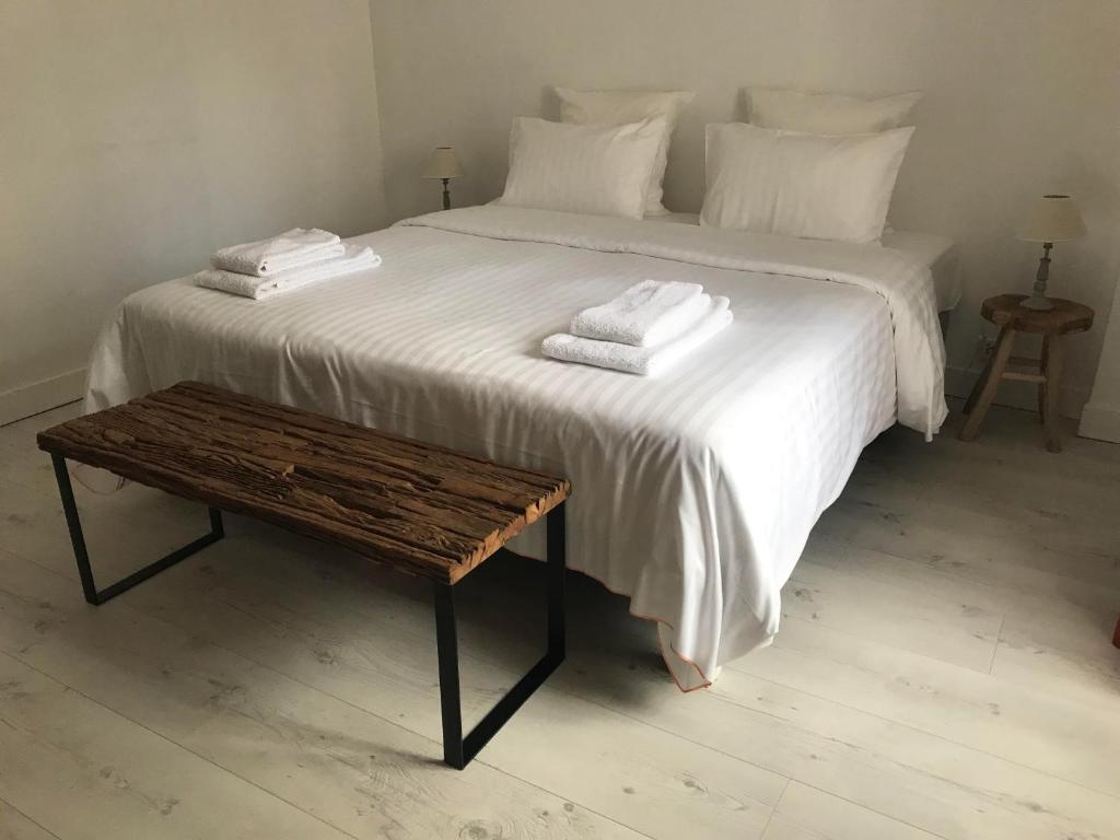 Una cama blanca con toallas encima y una mesa de madera. en Chablis Appart, en Chablis