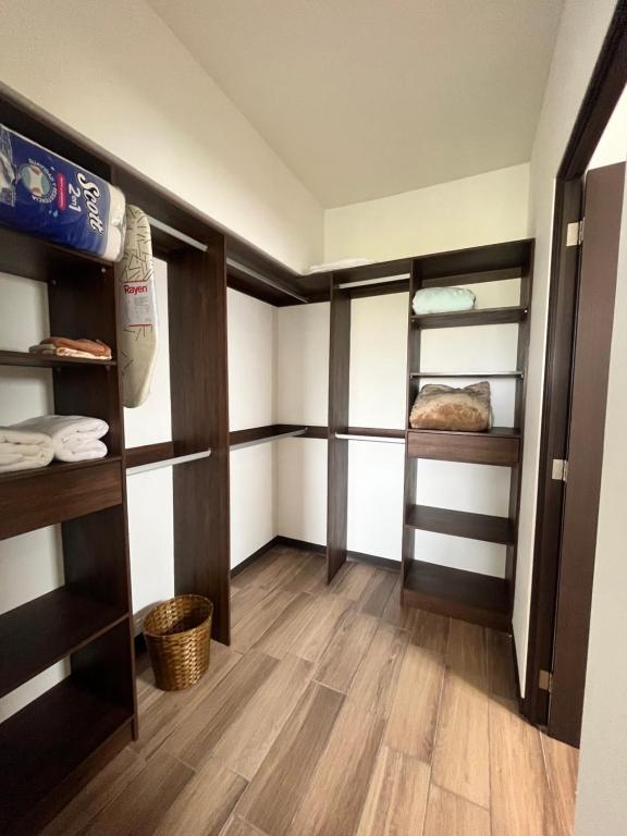 Cette chambre dispose d'étagères marron et de parquet. dans l'établissement Lindo apartamento cerca del aeropuerto, à Guatemala