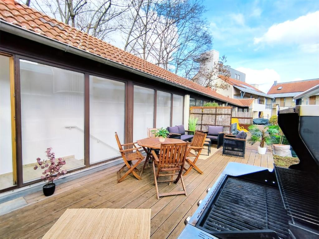 um pátio com uma mesa e cadeiras num deque em Design-Apartmenthaus für bis zu 12, modern, Dachterrasse, Grill, ruhige Lage, Disney plus, Wii, LAN und WLAN em Nuremberga