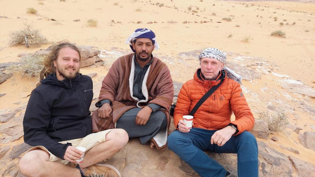 three men sitting on the sand in the desert at Wadi rum view camp in Wadi Rum