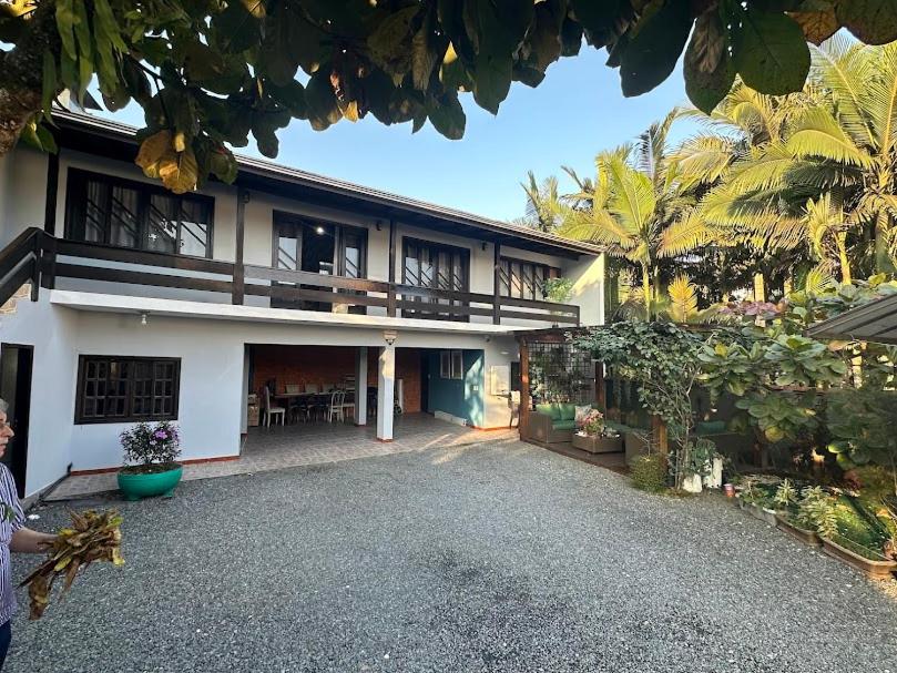 une femme debout devant une maison dans l'établissement Araújo Residence - Lar Doce Lar, à Joinville