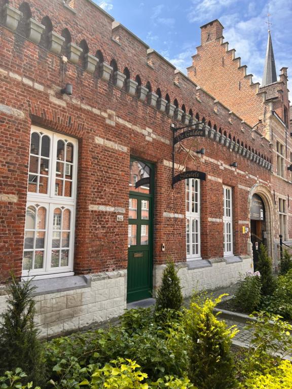 een rood bakstenen gebouw met een groene deur bij Vakantiewoning De Gulden Sleutels in Kruibeke