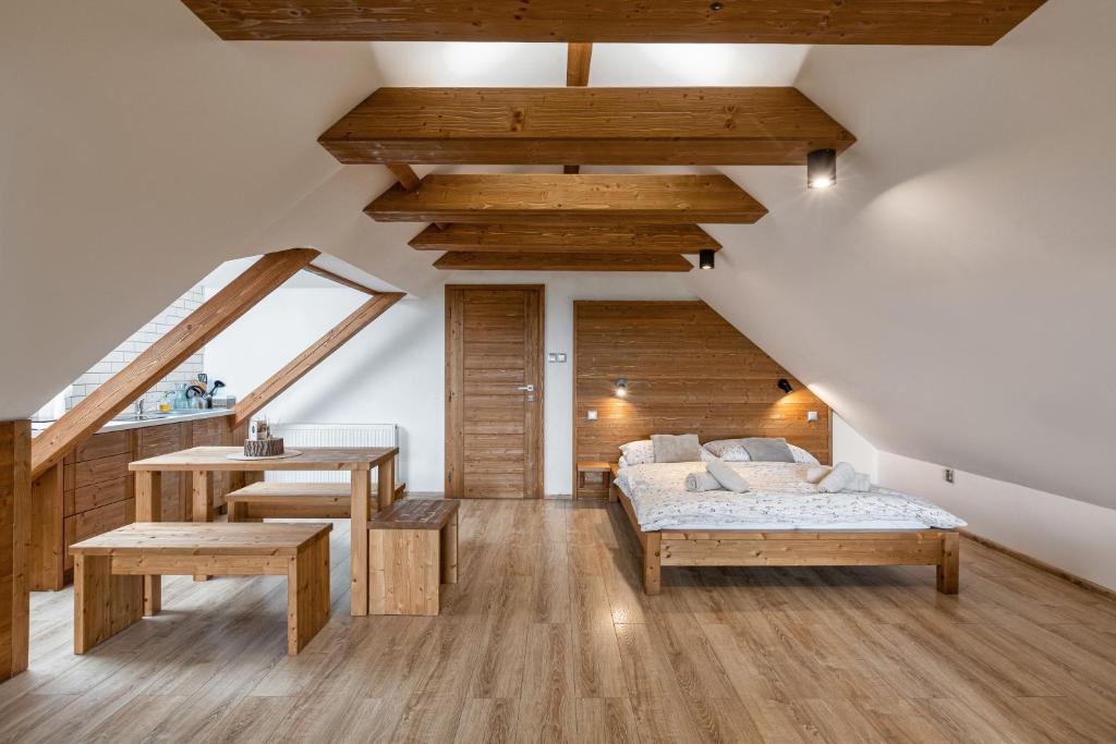 een slaapkamer met houten plafonds en een bed en een tafel bij Apartmány Nad Pivovarem in Havířov