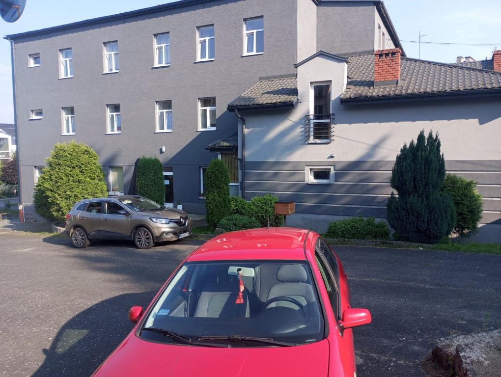 un'auto rossa parcheggiata in un parcheggio di fronte a un edificio di Gościniec Strwiąż a Ustrzyki Dolne