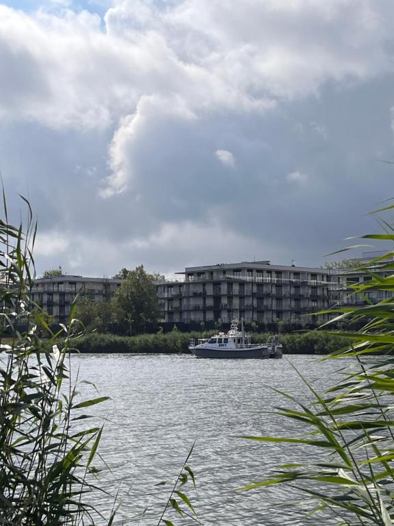 un barco en el agua frente a un edificio en Apartament Avalon SPA Dziwnów - basen sauna fitness, en Dziwnów