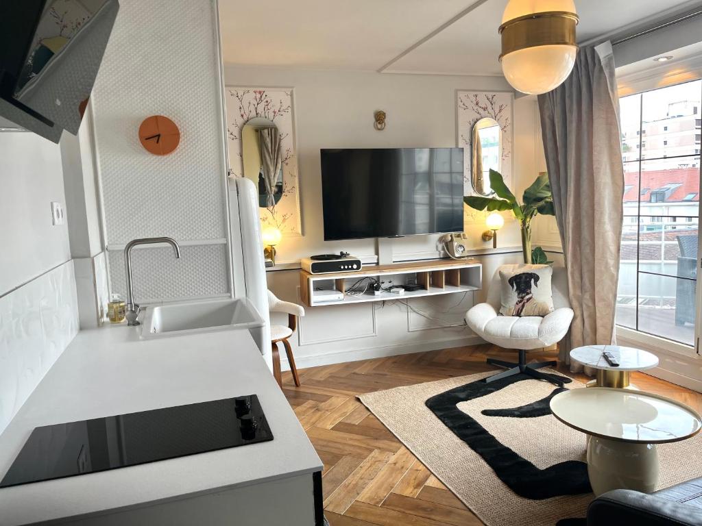 uma sala de estar com uma cozinha e uma televisão em le Boudoir de Longchamp em Suresnes