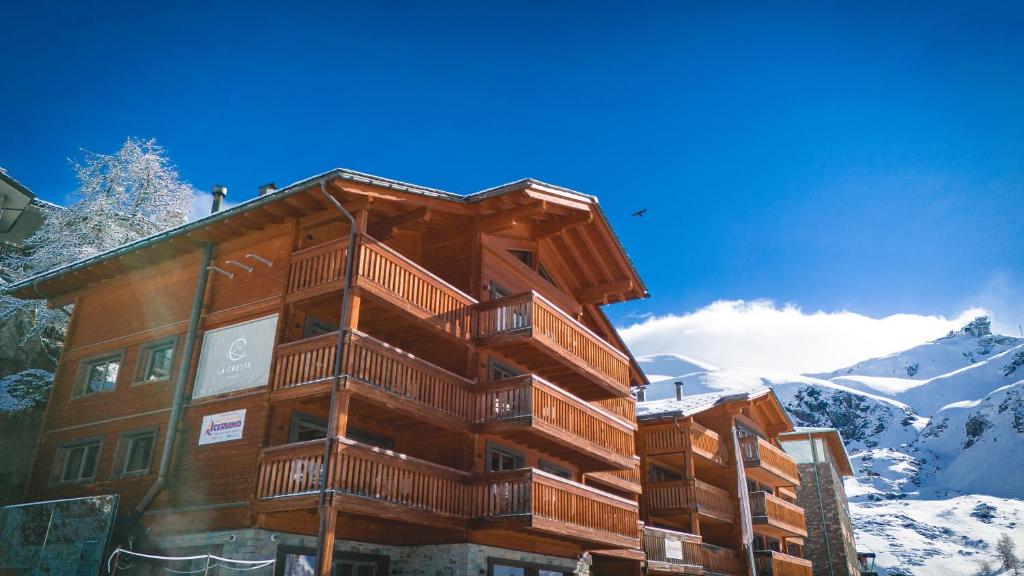 een groot houten gebouw met sneeuw op een berg bij La Cresta Chalet in Breuil-Cervinia