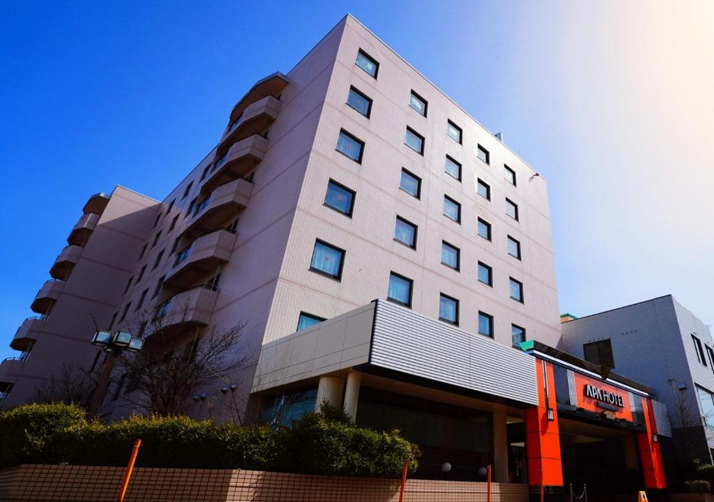 a tall white building with a bus in front of it at APA Hotel Kitakami Ekinishi in Kitakami