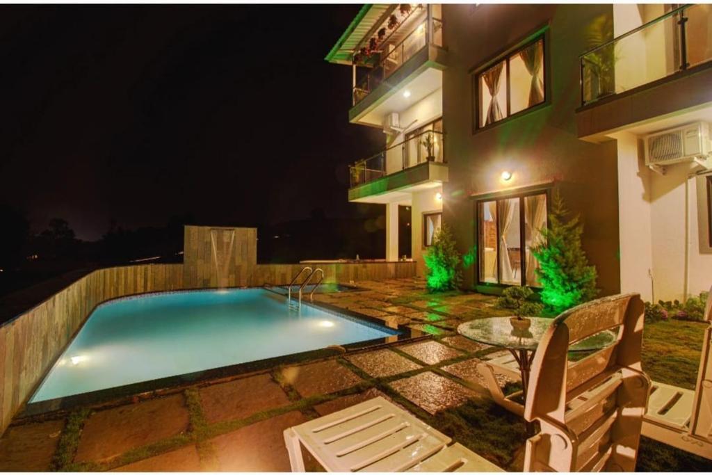 - une piscine en face d'un bâtiment la nuit dans l'établissement OCEAN CREST LUXURY VILLA Mahabaleshwar, à Mahabaleshwar