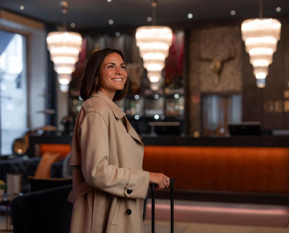 a woman in a trench coat holding a suitcase at Boutique Hotel Germania in Munich